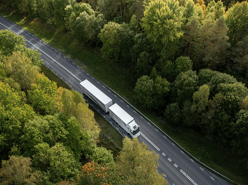 aktab-fossilfria-transporter-den-grona-vagen ÄKTAB lastbilsekipage rullar genom svensk skog på Den Gröna Vägen för hållbara transporter.
